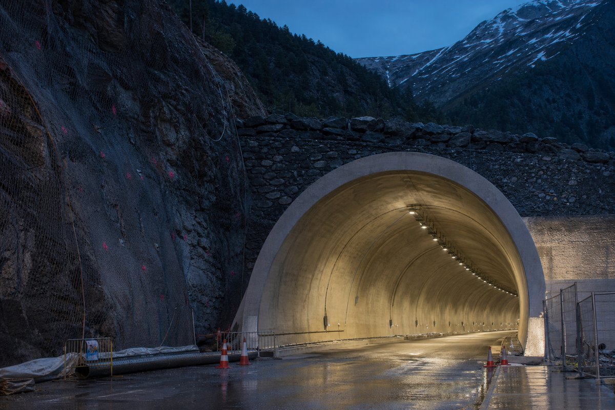 Road tunnel portal in Andorra: Pyrenean valley with a road tunnel portal, at blue hour with the portal lit, shot at 50mm, compressed. (AI-generated image)
