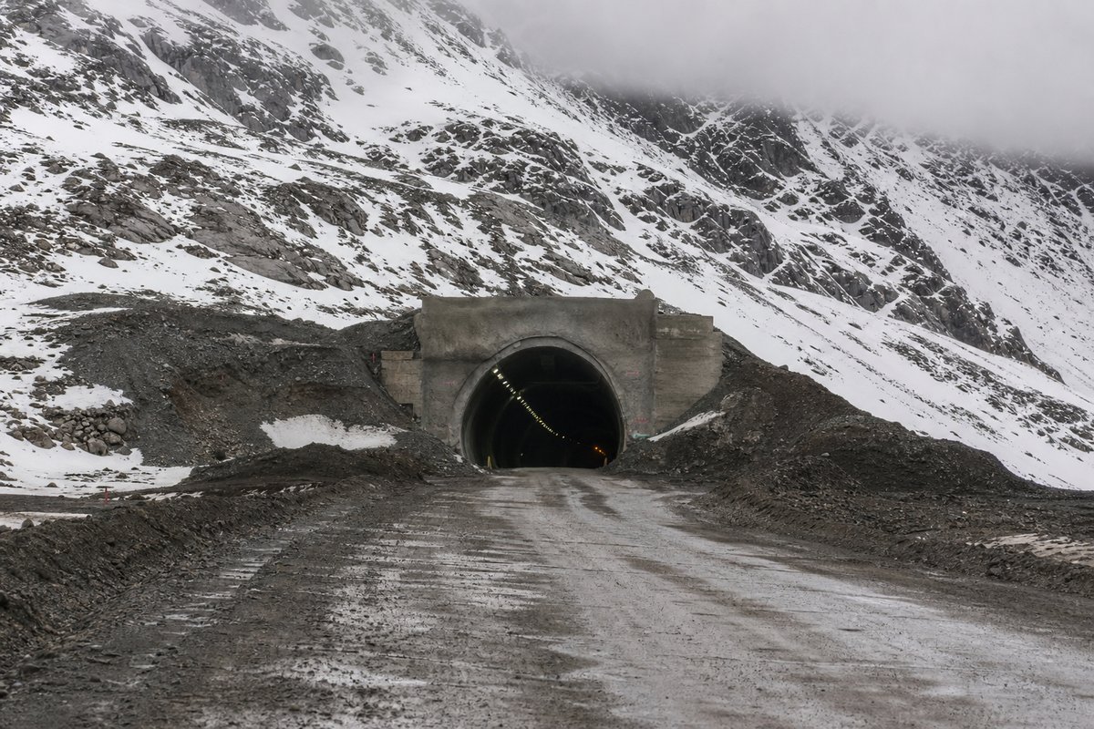 Road tunnel portal in Argentina: high Andean pass with a snow-covered tunnel portal, under low grey cloud, shot at 85mm from a distance. (AI-generated image)