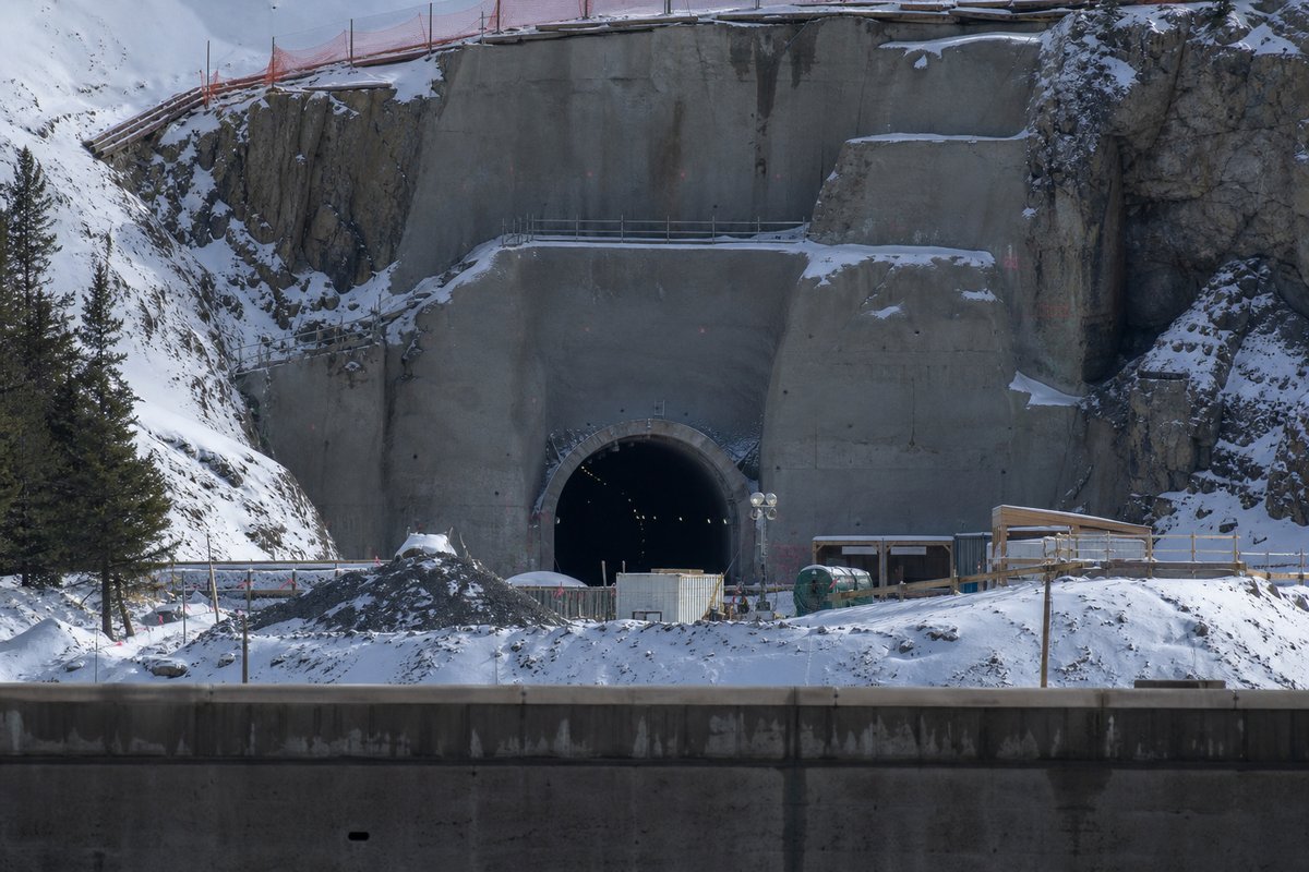 Road tunnel portal in Canada: Rocky Mountain rail corridor with a spiral tunnel portal in the snow, in hard low winter sun, shot at 85mm from a distance. (AI-generated image)