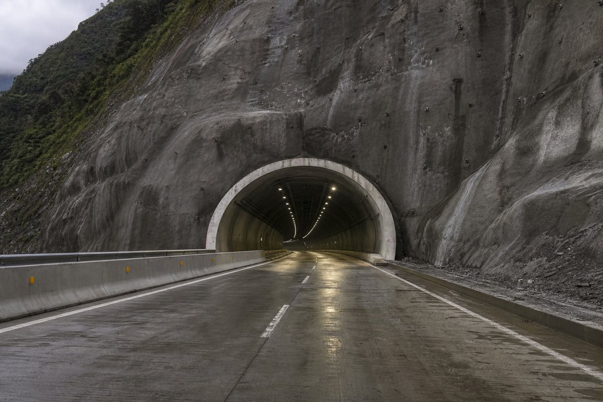 Road tunnel portal in Colombia: Andean cordillera with a long new highway tunnel portal, in flat overcast light, shot at 50mm, compressed. (AI-generated image)