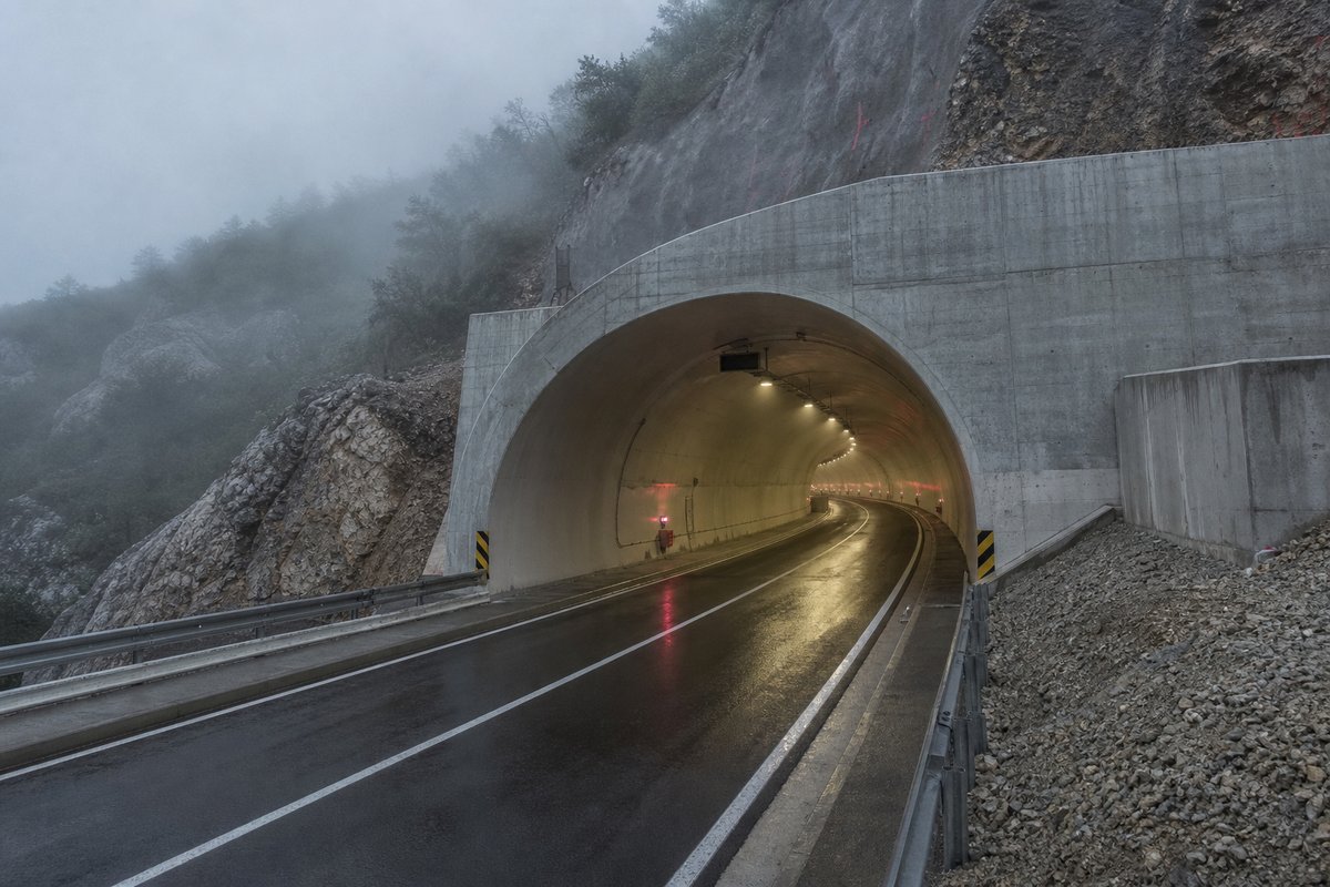 Road tunnel portal in Croatia: Dinaric karst, a motorway portal above the Adriatic, in drifting mist, shot at 35mm. (AI-generated image)
