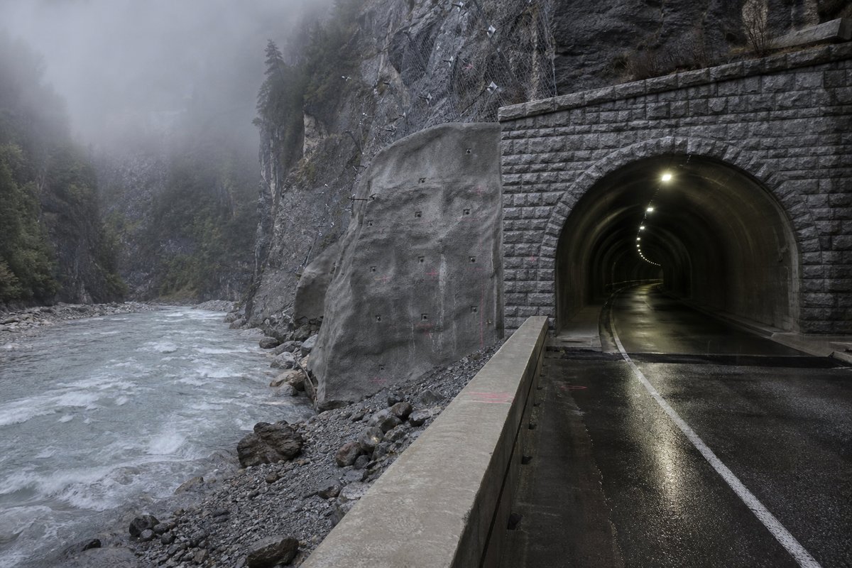 Transport infrastructure structure in France: Alpine gorge with a stone-faced tunnel mouth beside a river, in thin morning fog, shot at 35mm. (AI-generated image)