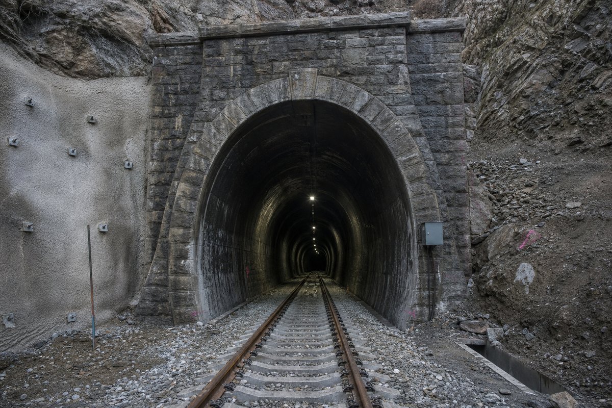 Road tunnel portal in Georgia: Caucasus slope with an old stone-lined railway tunnel, in cold clear light, shot wide at 24mm. (AI-generated image)