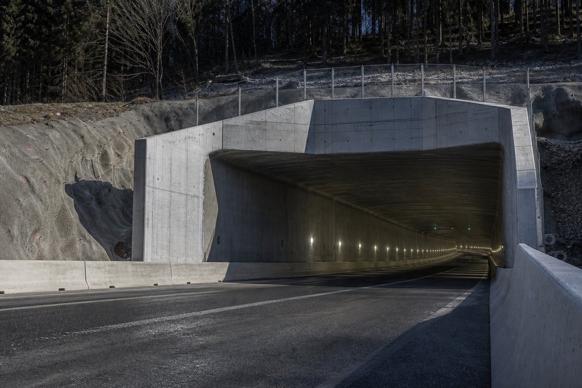Transport infrastructure structure in Germany: wooded low mountain range, a cut-and-cover portal in fair-faced concrete, in hard low winter sun. (AI-generated image)