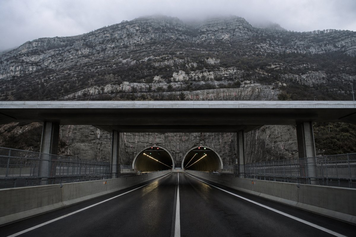 Motorway viaduct and tunnel portal in sequence along an autostrada in Italy: Apennine limestone ridge, twin concrete motorway portals with a projecting canopy. (AI-generated image)