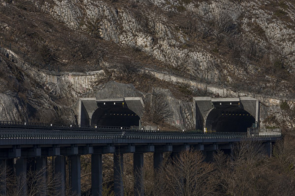 Motorway viaduct and tunnel portal in sequence along an autostrada in Italy: Apennine limestone ridge, twin concrete motorway portals with a projecting canopy. (AI-generated image)