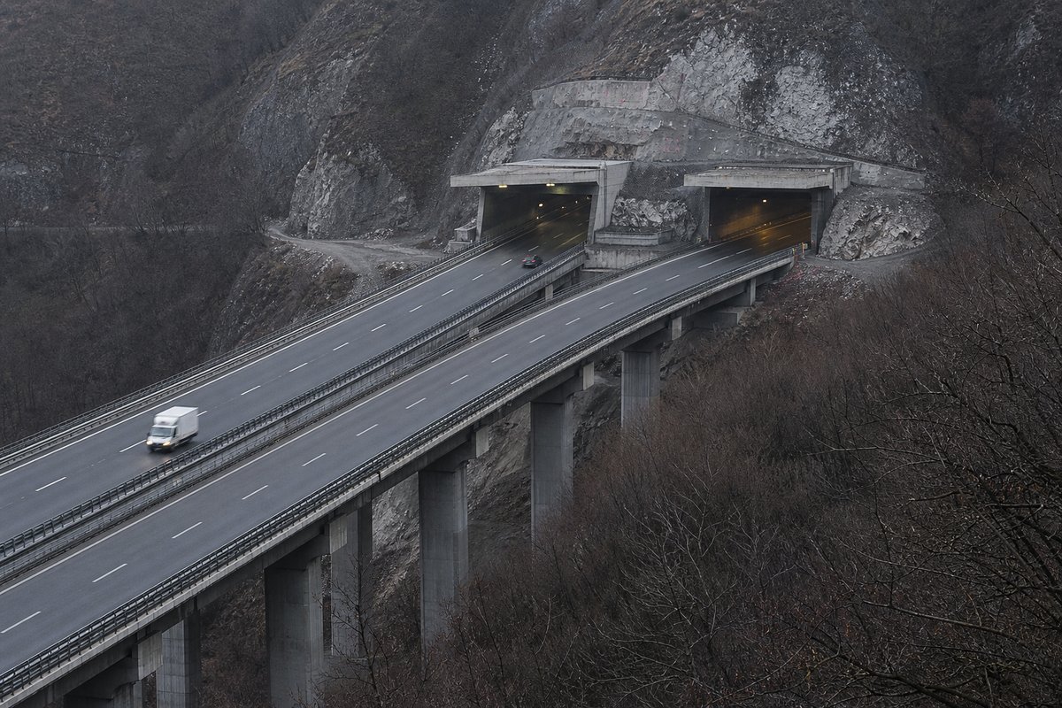 Motorway viaduct and tunnel portal in sequence along an autostrada in Italy: Apennine limestone ridge, twin concrete motorway portals with a projecting canopy. (AI-generated image)