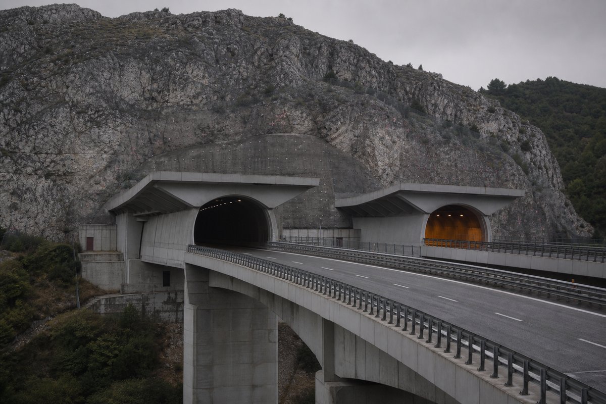 Motorway viaduct and tunnel portal in sequence along an autostrada in Italy: Apennine limestone ridge, twin concrete motorway portals with a projecting canopy. (AI-generated image)