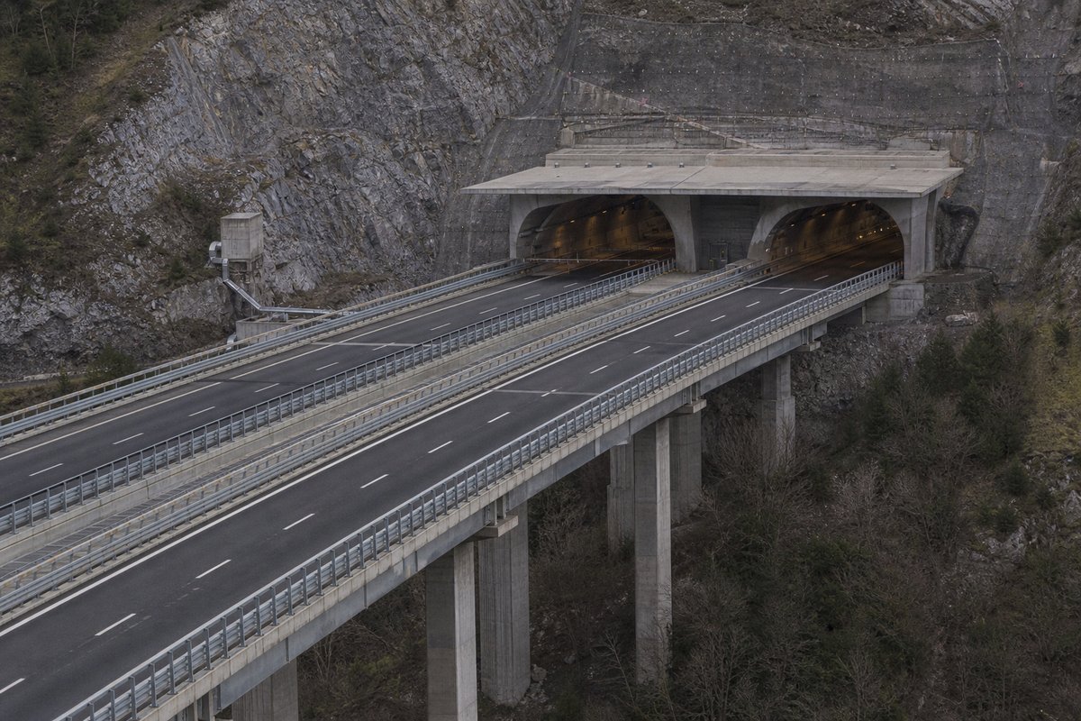 Motorway viaduct and tunnel portal in sequence along an autostrada in Italy: Apennine limestone ridge, twin concrete motorway portals with a projecting canopy. (AI-generated image)