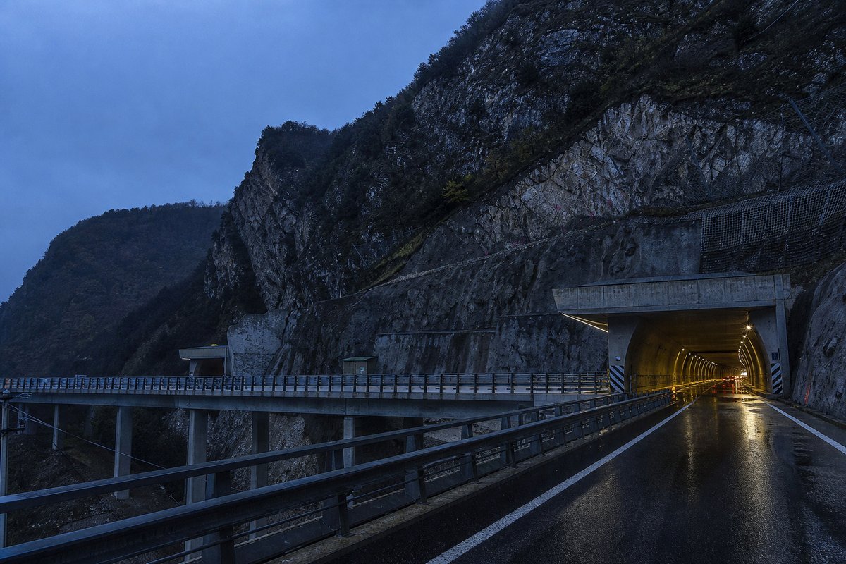 Motorway viaduct and tunnel portal in sequence along an autostrada in Italy: Apennine limestone ridge, twin concrete motorway portals with a projecting canopy. (AI-generated image)