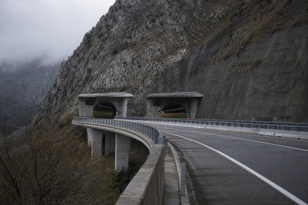 Motorway viaduct and tunnel portal in sequence along an autostrada in Italy: Apennine limestone ridge, twin concrete motorway portals with a projecting canopy. (AI-generated image)