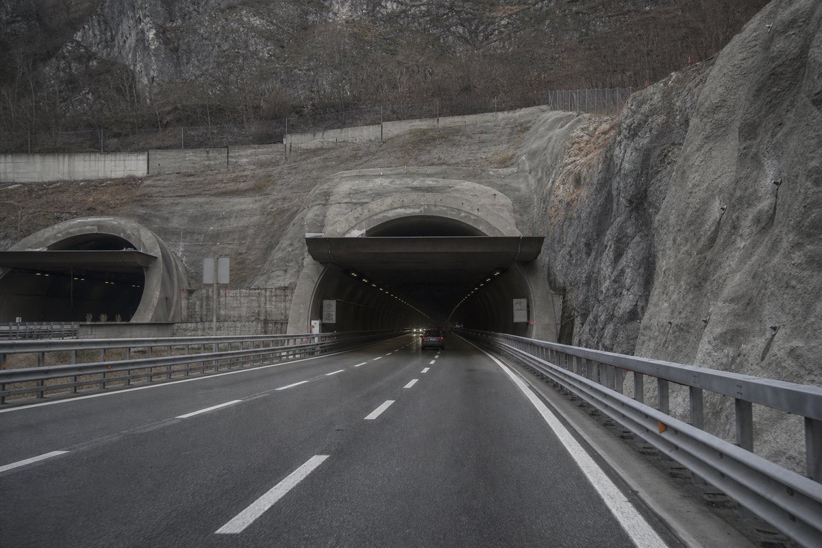 Motorway viaduct and tunnel portal in sequence along an autostrada in Italy: Apennine limestone ridge, twin concrete motorway portals with a projecting canopy. (AI-generated image)