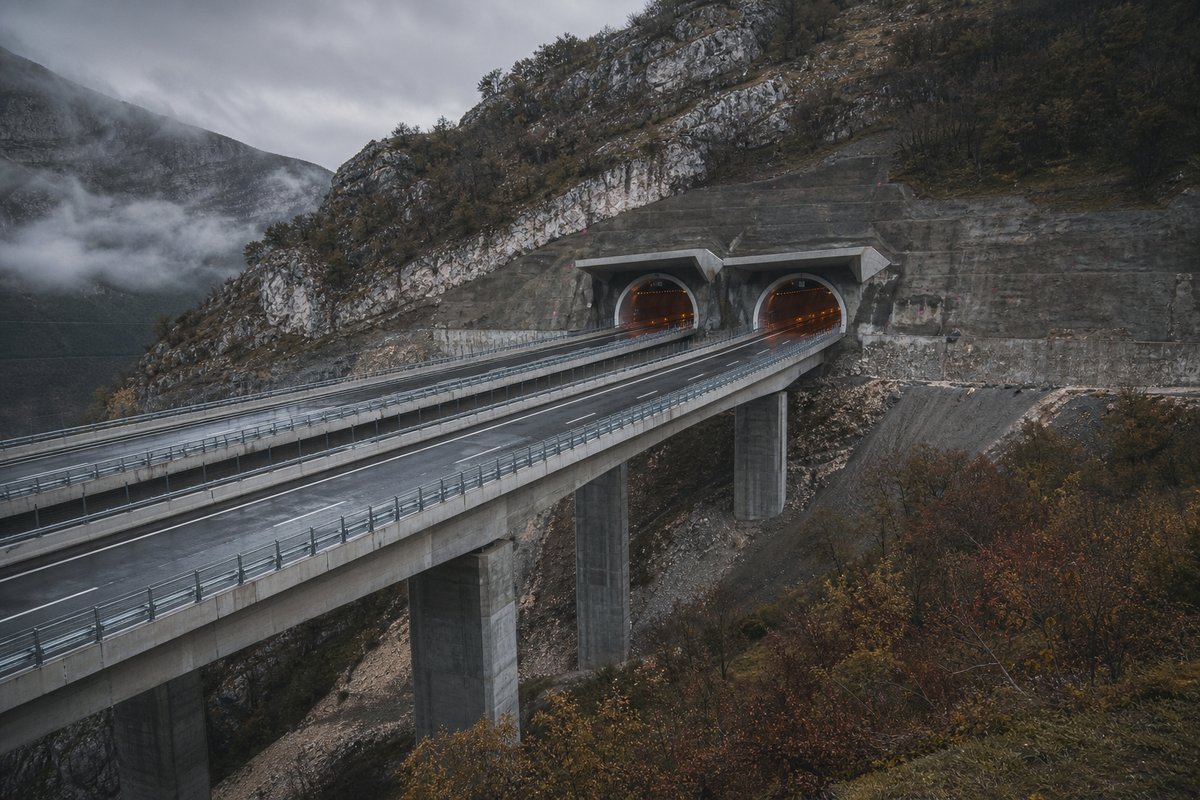 Motorway viaduct and tunnel portal in sequence along an autostrada in Italy: Apennine limestone ridge, twin concrete motorway portals with a projecting canopy. (AI-generated image)