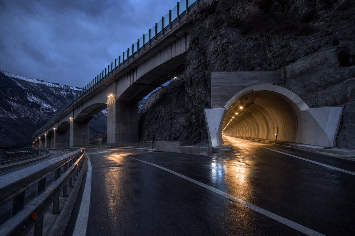 Motorway viaduct and tunnel portal in sequence along an autostrada in Italy: Apennine limestone ridge, twin concrete motorway portals with a projecting canopy. (AI-generated image)
