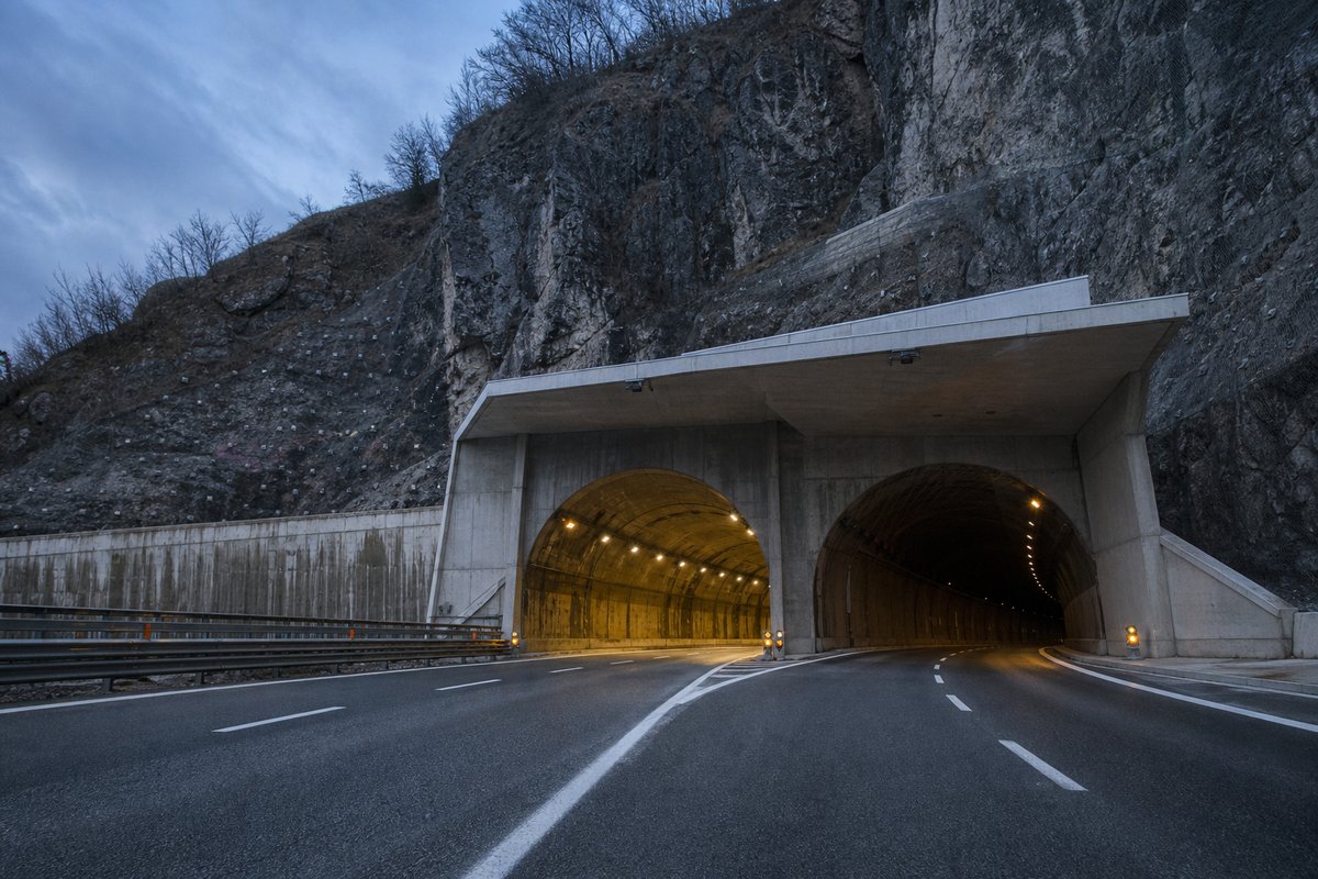 Motorway viaduct and tunnel portal in sequence along an autostrada in Italy: Apennine limestone ridge, twin concrete motorway portals with a projecting canopy. (AI-generated image)
