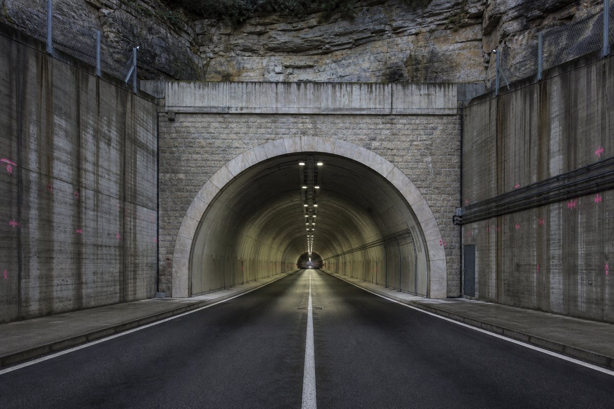 Road tunnel portal in Luxembourg: sandstone plateau edge, a short urban road tunnel portal, in cold clear light, a dead-centre symmetrical composition. (AI-generated image)