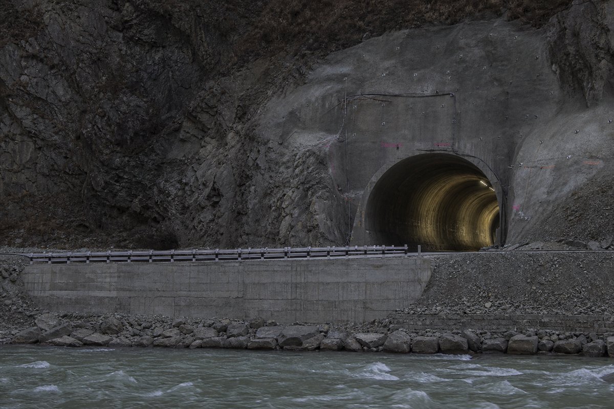 Transport infrastructure structure in Nepal: Himalayan river valley with a newly bored road tunnel, in flat overcast light, shot at 85mm from a distance. (AI-generated image)