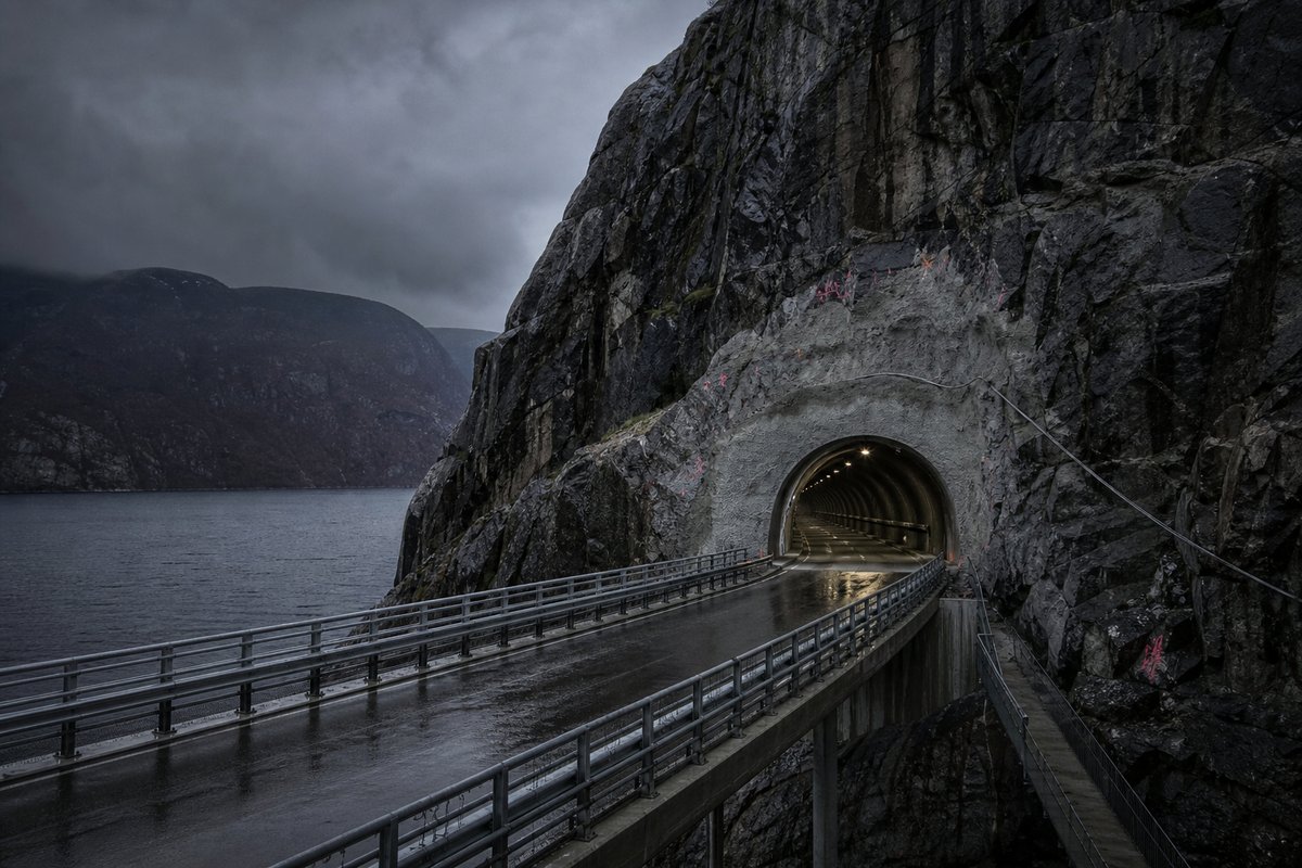 Transport infrastructure structure in Norway: steep granite fjord wall, dark water below, a rock-cut tunnel portal with no decoration, under a heavy dark sky. (AI-generated image)