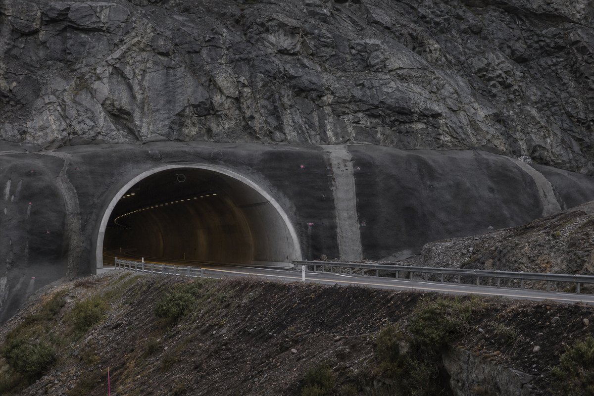 Road tunnel portal in Portugal: Atlantic granite hillside with a motorway tunnel mouth, in flat overcast light, shot at 85mm from a distance. (AI-generated image)