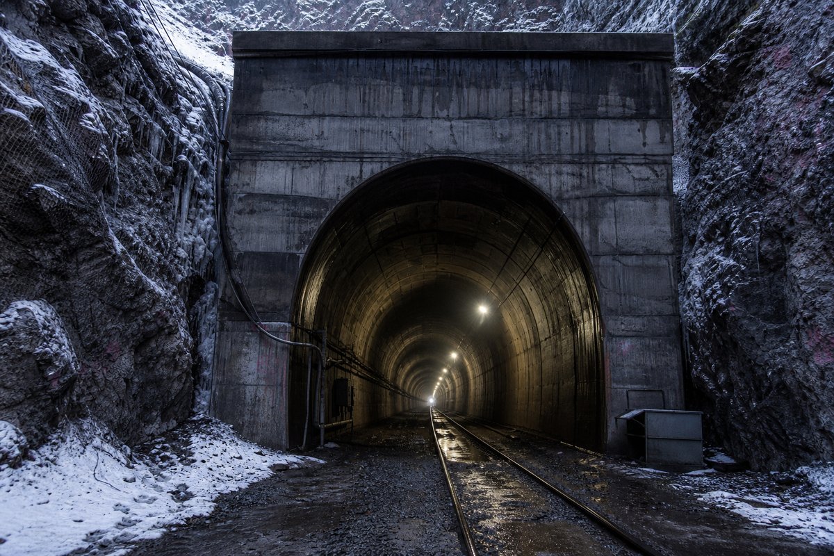 Road tunnel portal in Russia: Siberian rock cutting with a heavy railway tunnel portal in snow, in drifting mist, shot wide at 24mm. (AI-generated image)