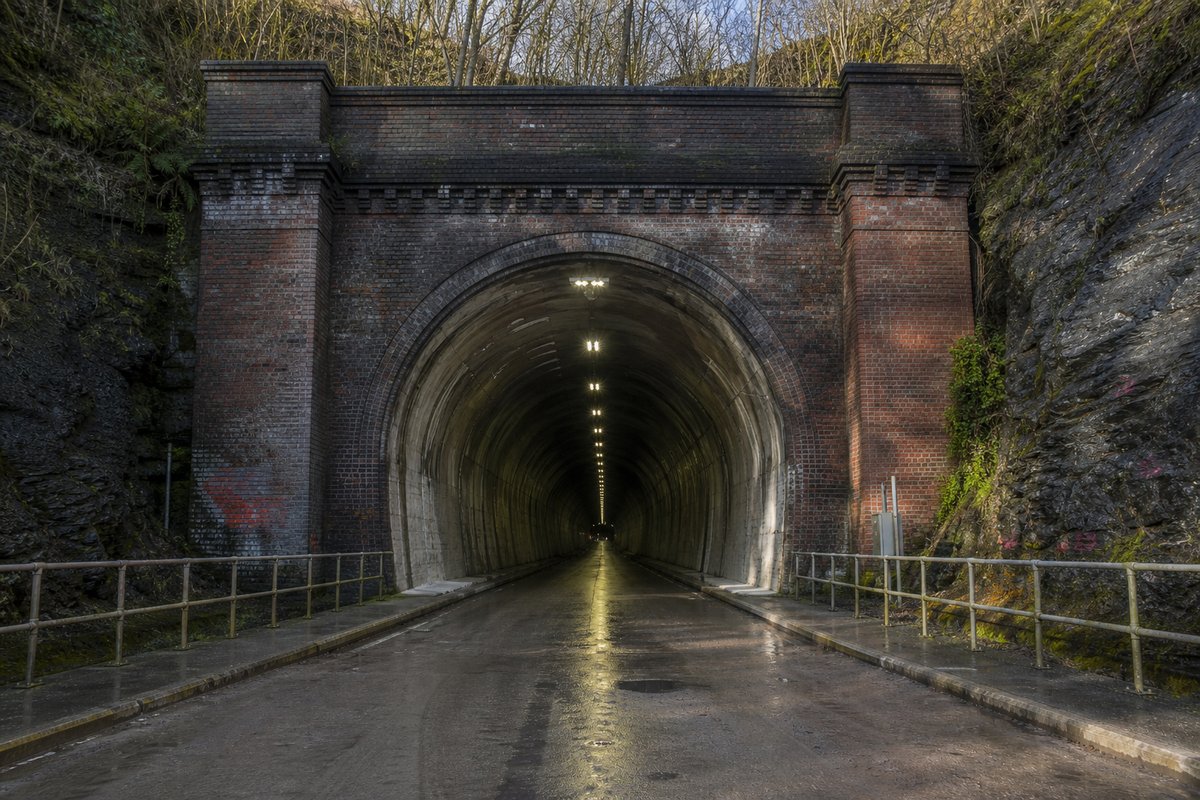 Road tunnel portal in the United Kingdom: a mountainous transport corridor, in hard low winter sun, shot at 35mm. (AI-generated image)